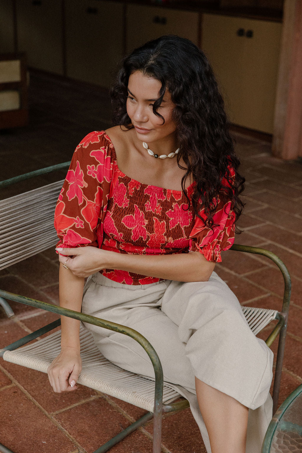 woman wearing versatile smocked top with off the shoulder on the shoulder sleeves in a vibrant retro pink pua print