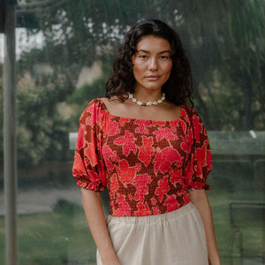 woman wearing versatile smocked top with off the shoulder on the shoulder sleeves in a vibrant retro pink pua print