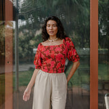 woman wearing versatile smocked top with off the shoulder on the shoulder sleeves in a vibrant retro pink pua print