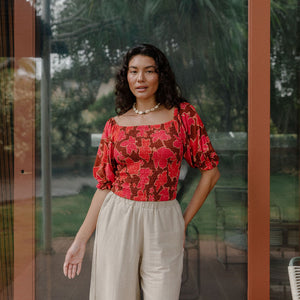 woman wearing versatile smocked top with off the shoulder on the shoulder sleeves in a vibrant retro pink pua print