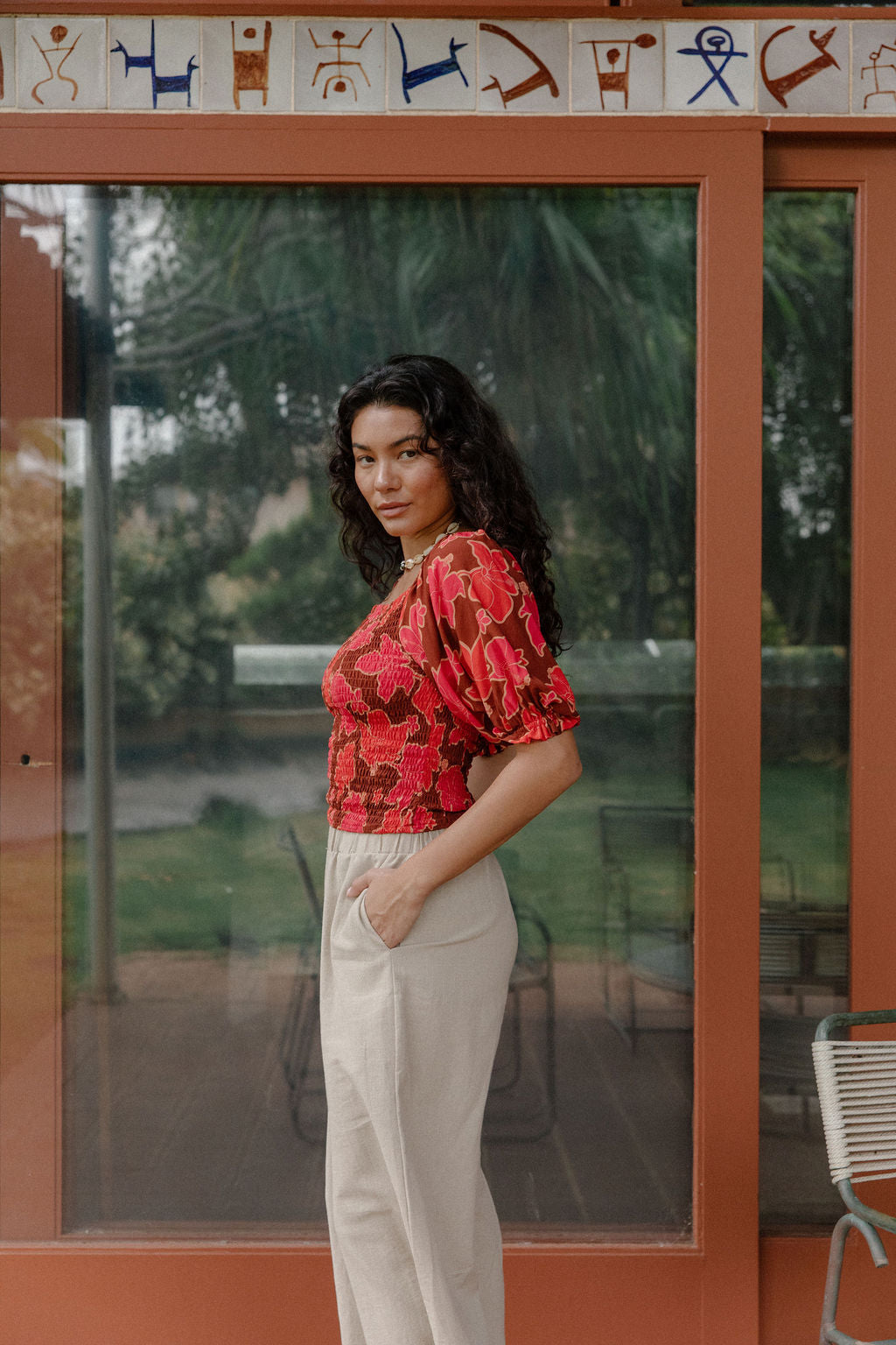 woman wearing versatile smocked top with off the shoulder on the shoulder sleeves in a vibrant retro pink pua print