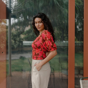 woman wearing versatile smocked top with off the shoulder on the shoulder sleeves in a vibrant retro pink pua print