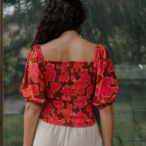 woman wearing versatile smocked top with off the shoulder on the shoulder sleeves in a vibrant retro pink pua print