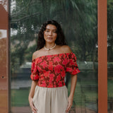 woman wearing versatile smocked top with off the shoulder on the shoulder sleeves in a vibrant retro pink pua print