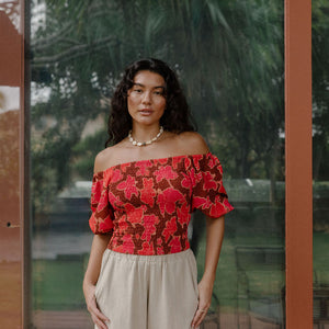 woman wearing versatile smocked top with off the shoulder on the shoulder sleeves in a vibrant retro pink pua print