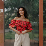 woman wearing versatile smocked top with off the shoulder on the shoulder sleeves in a vibrant retro pink pua print