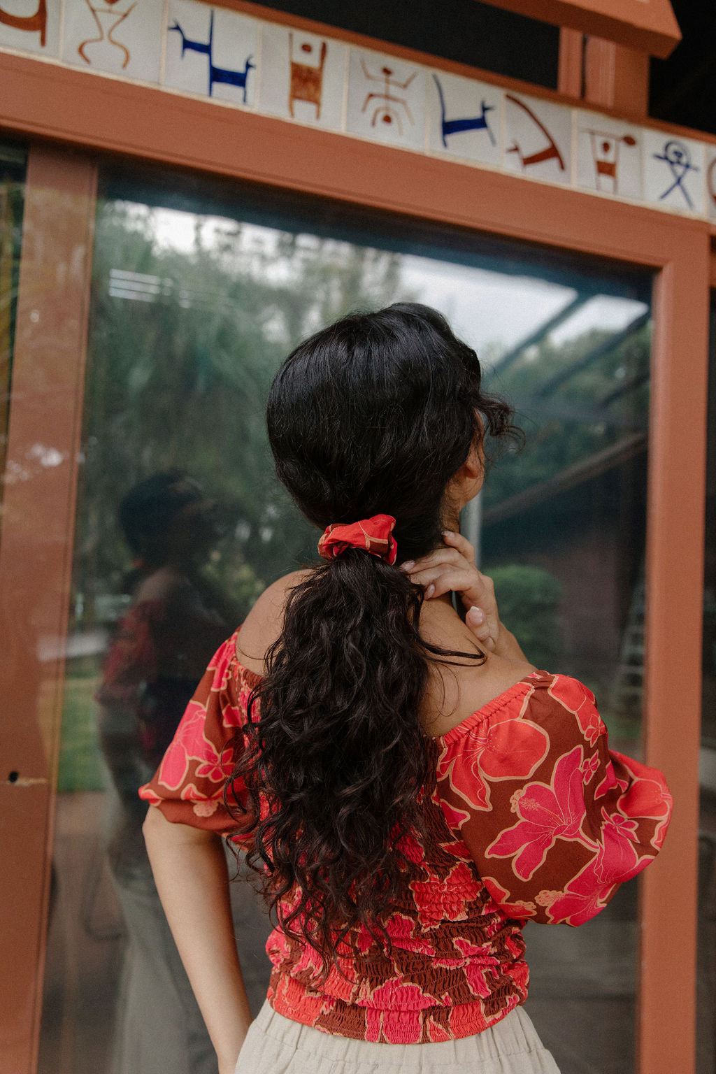 woman wearing versatile smocked top with off the shoulder on the shoulder sleeves in a vibrant retro pink pua print