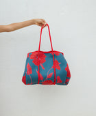 large neoprene tote bag and matching pouch in a bright teal and red mao flower pattern