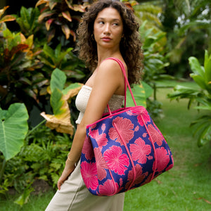 woman carrying large dark navy blue everyday tote bag with rope straps, detachable mini pouch, and bright pink hibiscus print