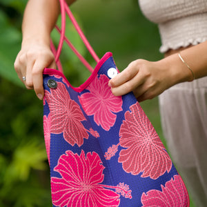woman carrying large dark navy blue everyday tote bag with rope straps, detachable mini pouch, and bright pink hibiscus print