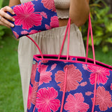 woman carrying large dark navy blue everyday tote bag with rope straps, detachable mini pouch, and bright pink hibiscus print