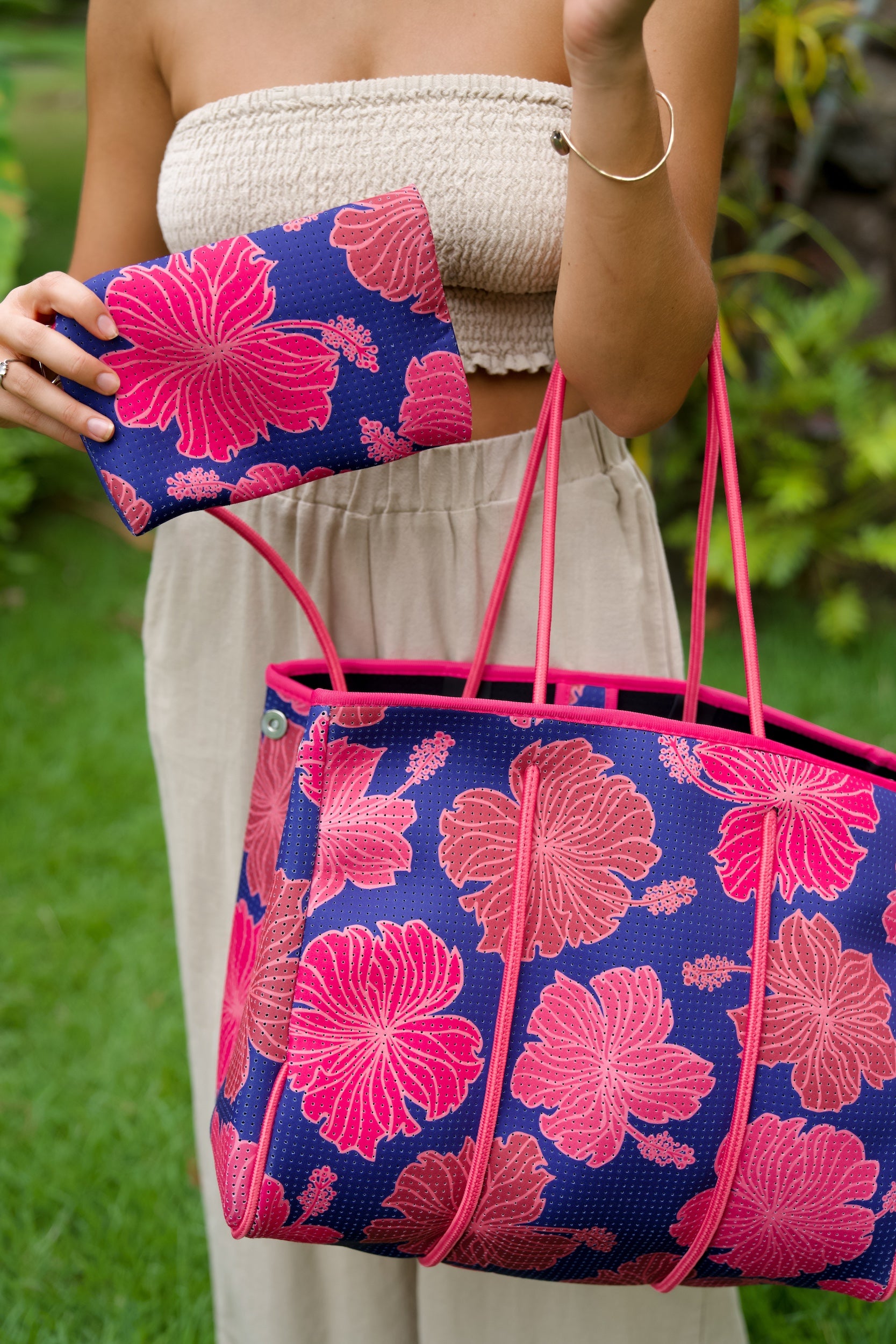 woman carrying large dark navy blue everyday tote bag with rope straps, detachable mini pouch, and bright pink hibiscus print