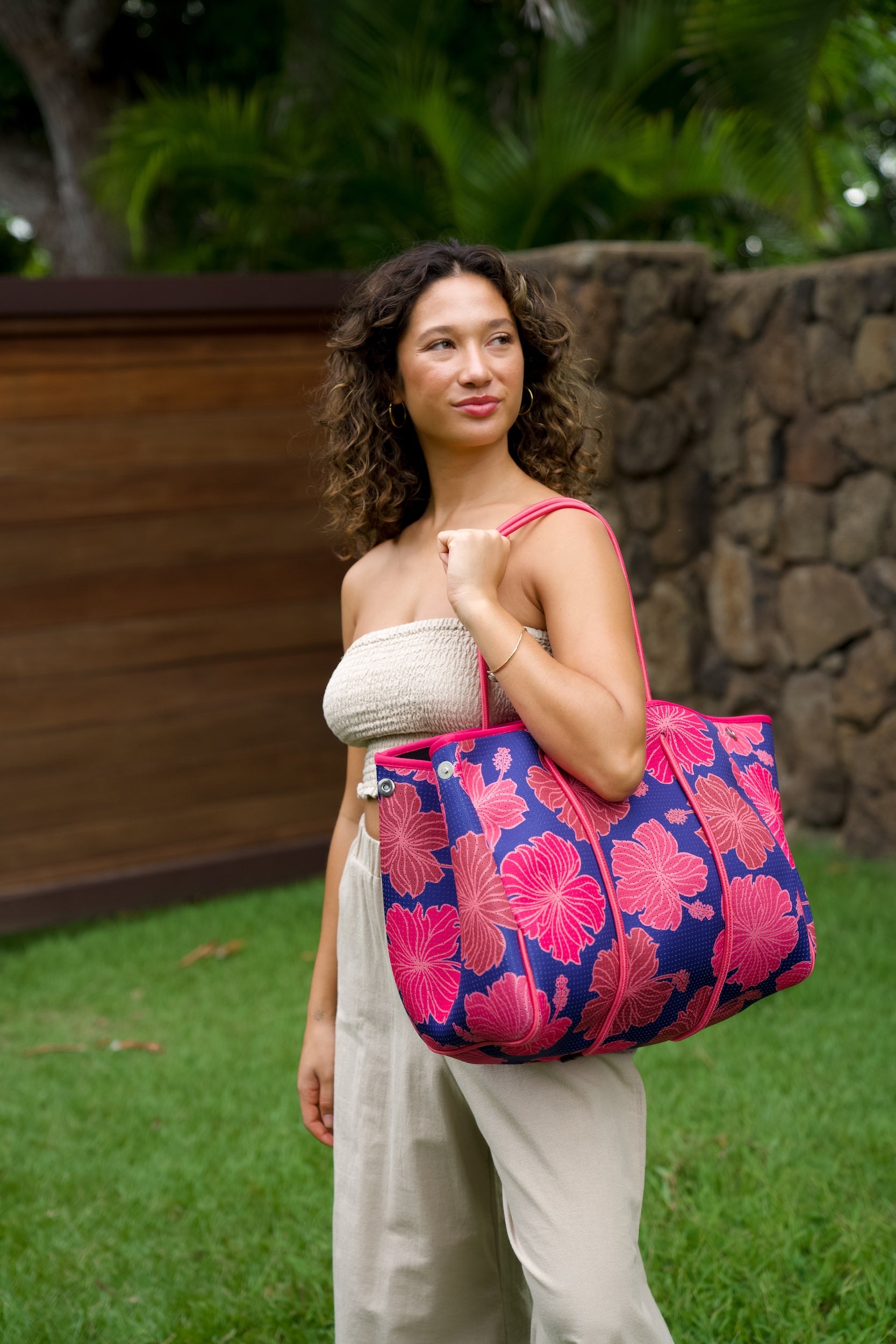 woman carrying large dark navy blue everyday tote bag with rope straps, detachable mini pouch, and bright pink hibiscus print