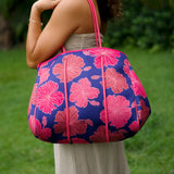 woman carrying large dark navy blue everyday tote bag with rope straps, detachable mini pouch, and bright pink hibiscus print