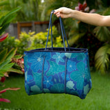 woman carrying large dark navy blue everyday tote bag with rope straps, detachable mini pouch, and blue/green flower print