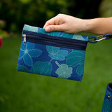 woman carrying large dark navy blue everyday tote bag with rope straps, detachable mini pouch, and blue/green flower print