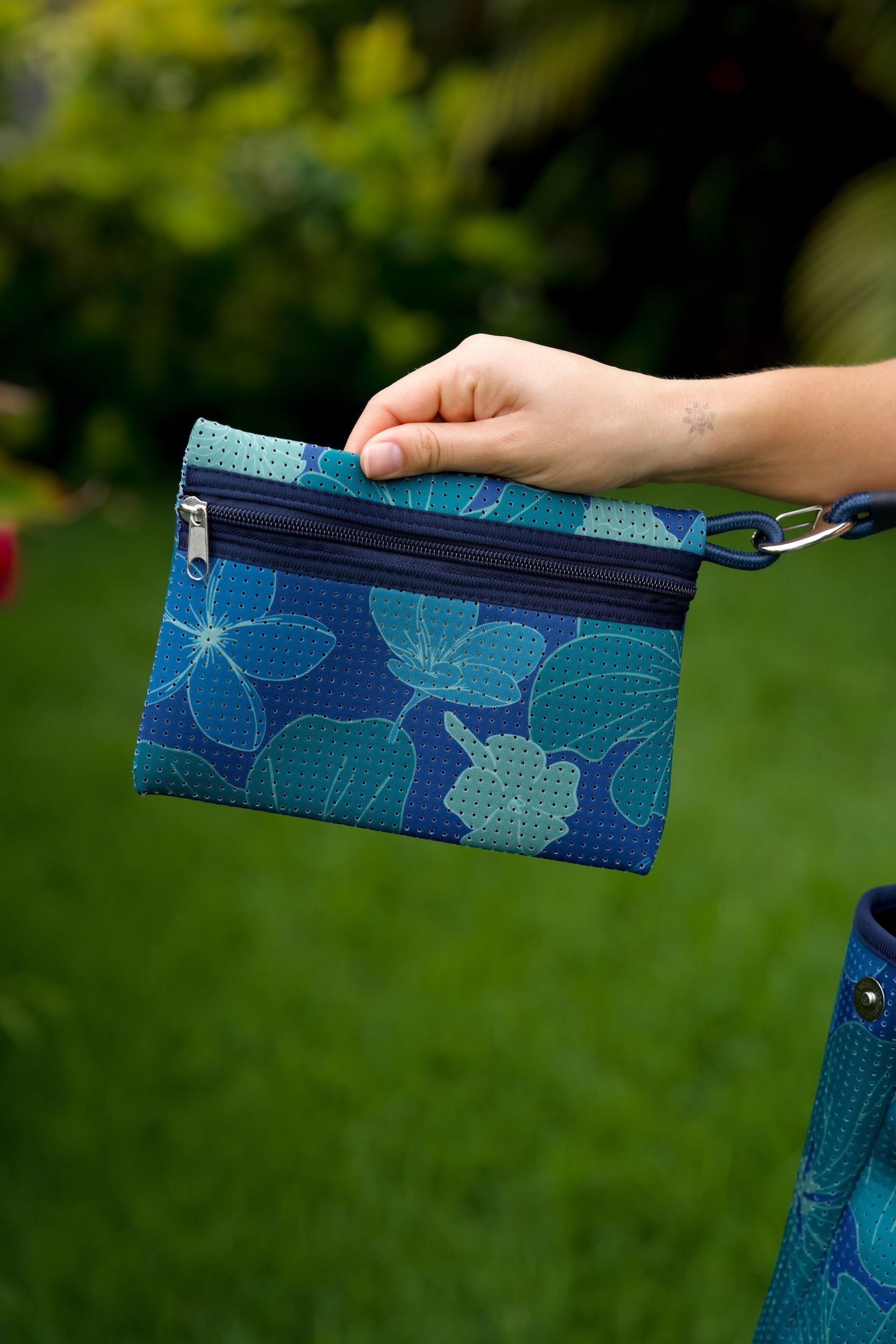 woman carrying large dark navy blue everyday tote bag with rope straps, detachable mini pouch, and blue/green flower print