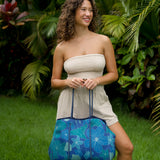 woman carrying large dark navy blue everyday tote bag with rope straps, detachable mini pouch, and blue/green flower print