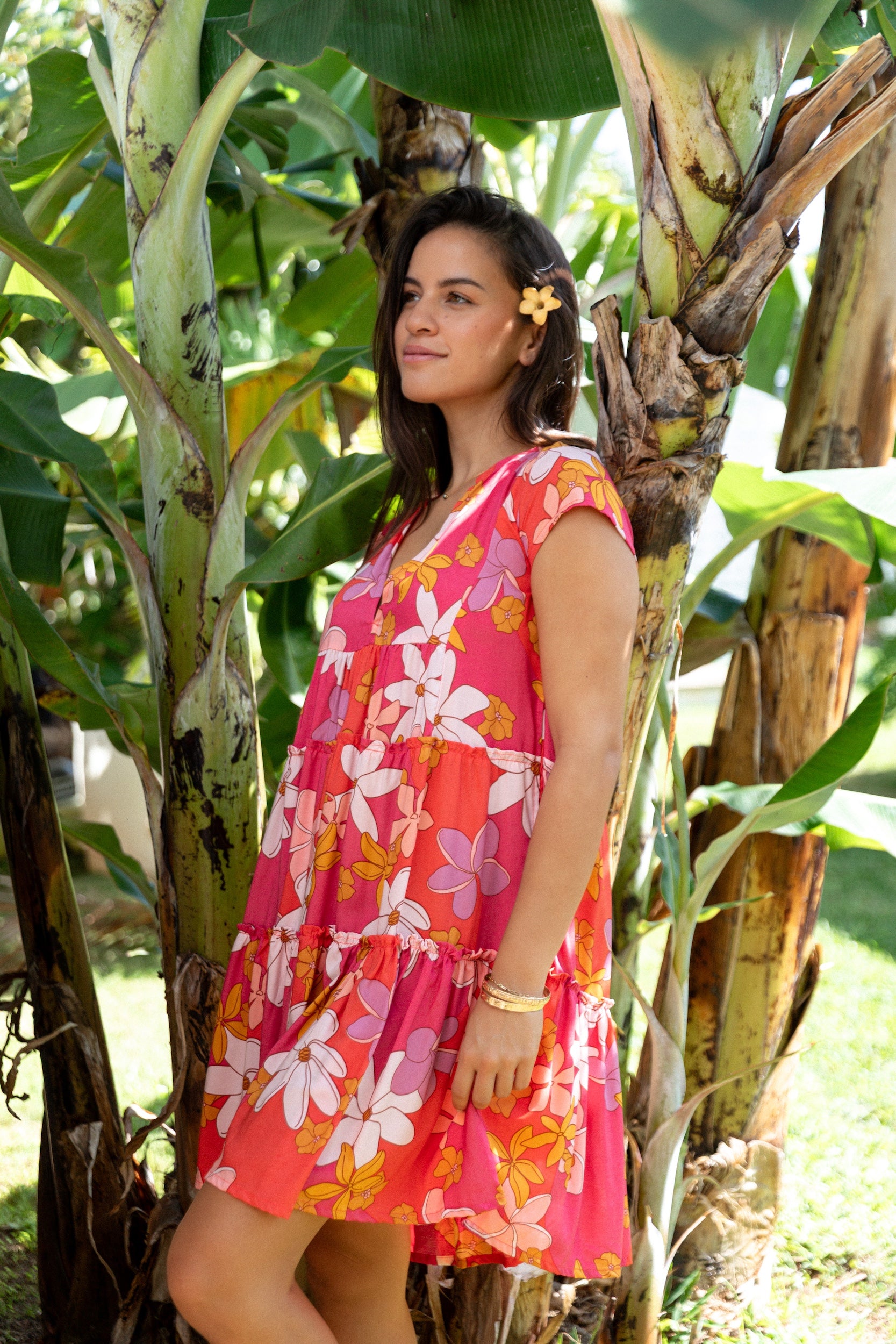 woman with brown hair wearing a pink short sleeve tiered mini dress with retro flower print