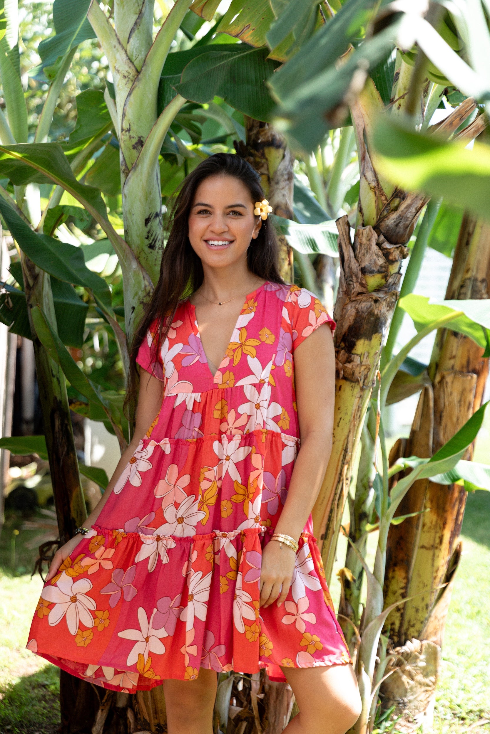 woman with brown hair wearing a pink short sleeve tiered mini dress with retro flower print
