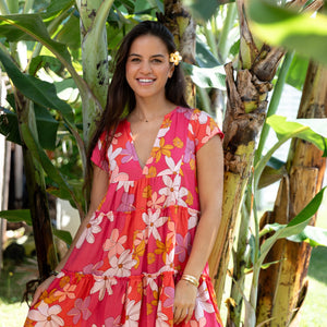 woman with brown hair wearing a pink short sleeve tiered mini dress with retro flower print