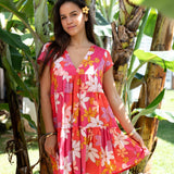 woman with brown hair wearing a pink short sleeve tiered mini dress with retro flower print