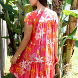 woman with brown hair wearing a pink short sleeve tiered mini dress with retro flower print