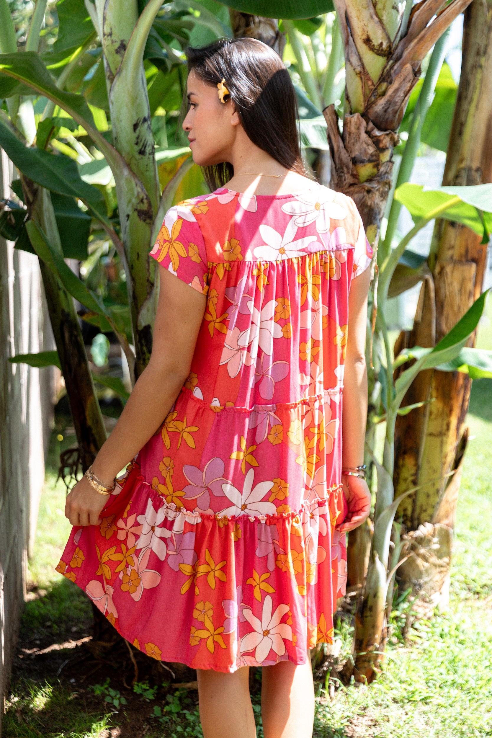 woman with brown hair wearing a pink short sleeve tiered mini dress with retro flower print
