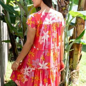 woman with brown hair wearing a pink short sleeve tiered mini dress with retro flower print