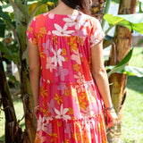 woman with brown hair wearing a pink short sleeve tiered mini dress with retro flower print