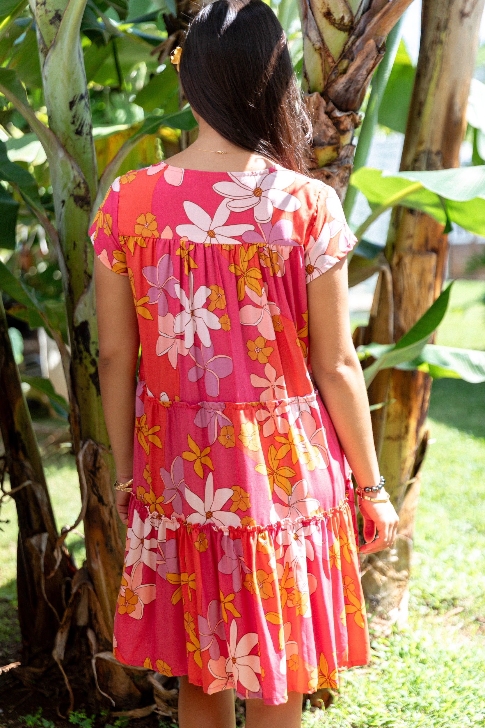 woman with brown hair wearing a pink short sleeve tiered mini dress with retro flower print
