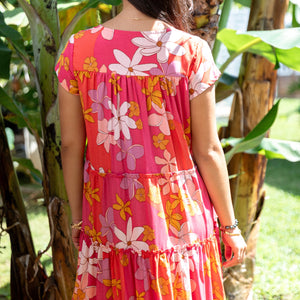 woman with brown hair wearing a pink short sleeve tiered mini dress with retro flower print