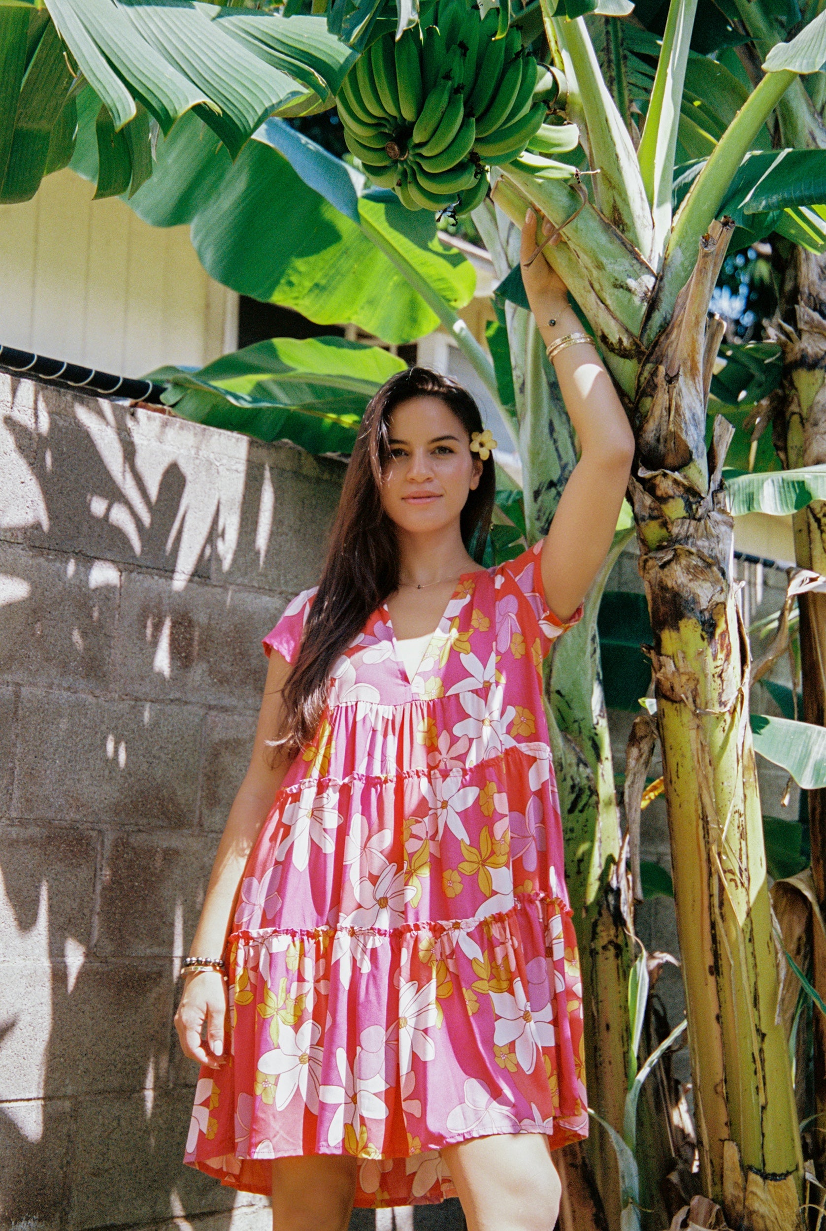 woman with brown hair wearing a pink short sleeve tiered mini dress with retro flower print