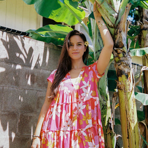 woman with brown hair wearing a pink short sleeve tiered mini dress with retro flower print
