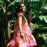 woman with brown hair wearing a pink short sleeve tiered mini dress with retro flower print