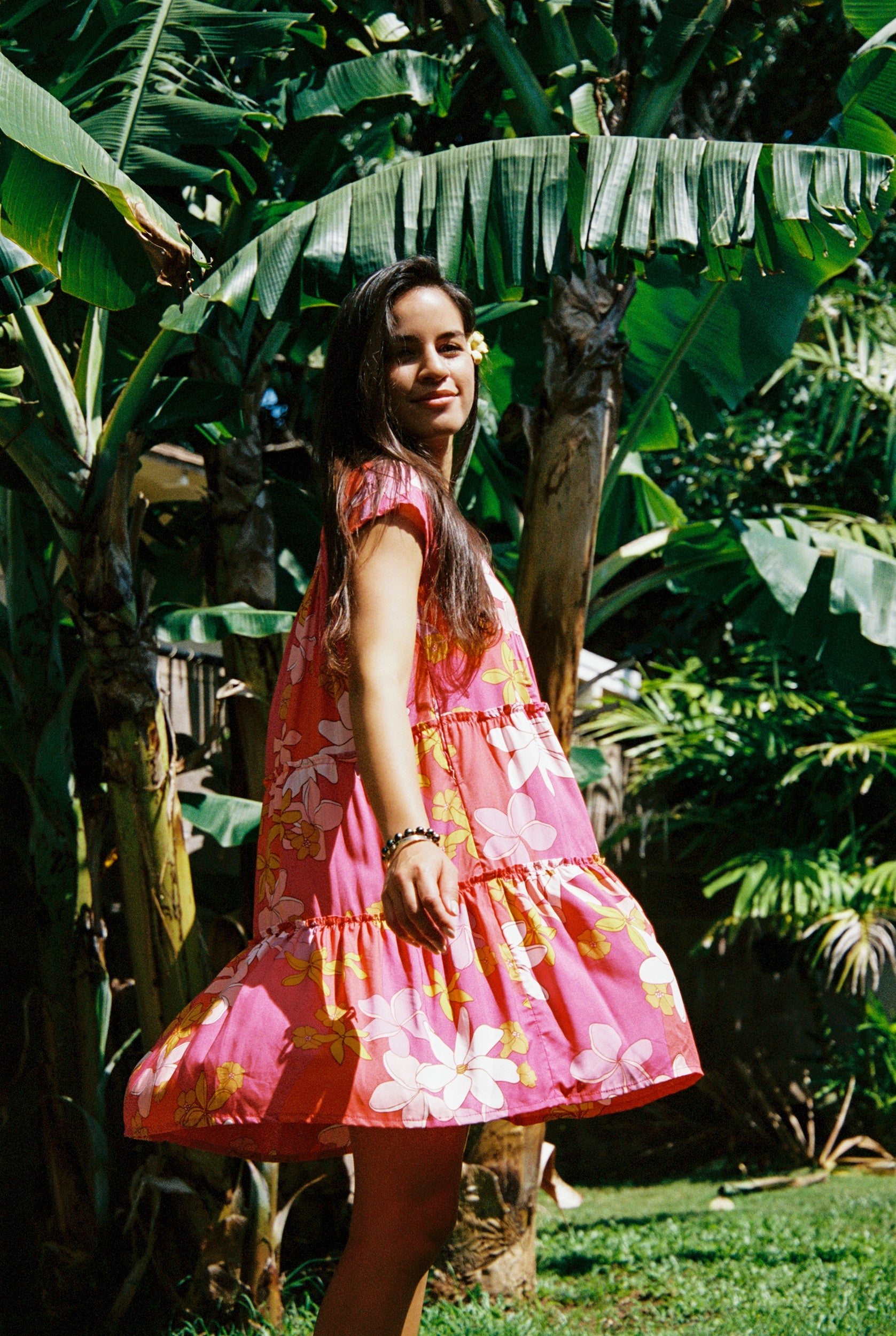 woman with brown hair wearing a pink short sleeve tiered mini dress with retro flower print