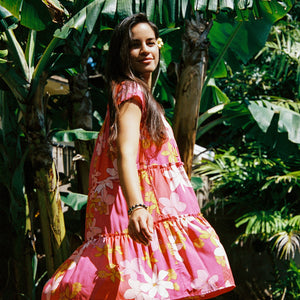 woman with brown hair wearing a pink short sleeve tiered mini dress with retro flower print
