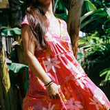 woman with brown hair wearing a pink short sleeve tiered mini dress with retro flower print