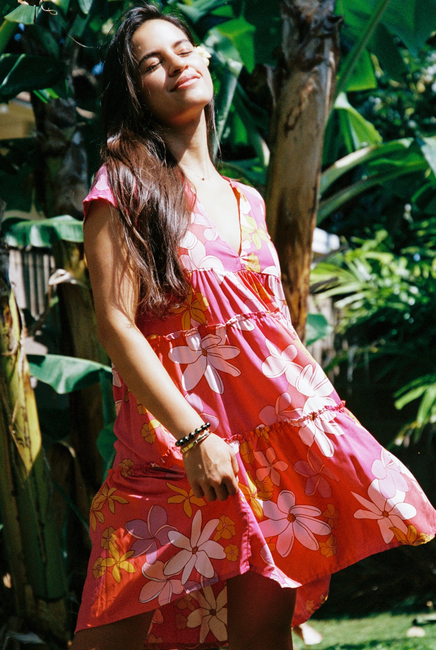 woman with brown hair wearing a pink short sleeve tiered mini dress with retro flower print