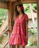 A woman with dark hair wears a YIREH tiered flowy dress. It is the Florentine Dress in the Garden 'Awapuhi print. 