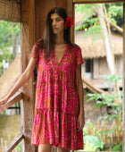 A woman with dark hair wears a YIREH tiered flowy dress. It is the Florentine Dress in the Garden 'Awapuhi print. 