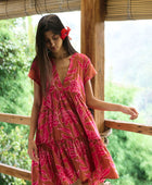 A woman with dark hair wears a YIREH tiered flowy dress. It is the Florentine Dress in the Garden 'Awapuhi print. 