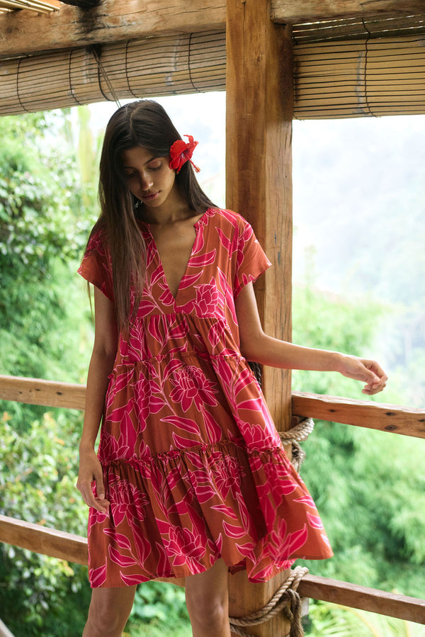 A woman with dark hair wears a YIREH tiered flowy dress. It is the Florentine Dress in the Garden 'Awapuhi print. 