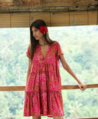 A woman with dark hair wears a YIREH tiered flowy dress. It is the Florentine Dress in the Garden 'Awapuhi print. 