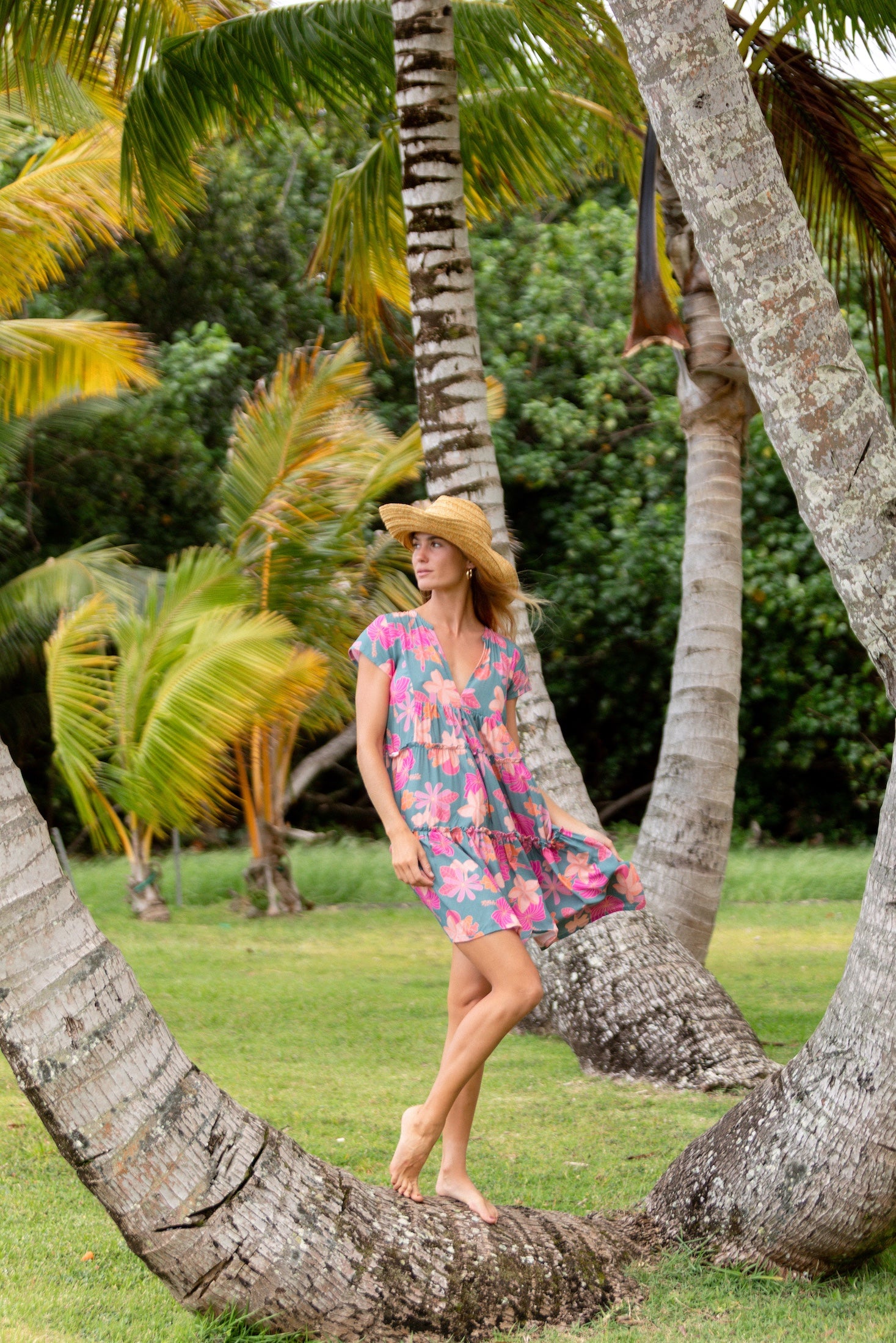 woman with brown hair wearing a teal v neck flowy dress with orange and pink floral print