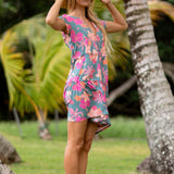 woman with brown hair wearing a teal v neck flowy dress with orange and pink floral print