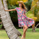 woman with brown hair wearing a teal v neck flowy dress with orange and pink floral print