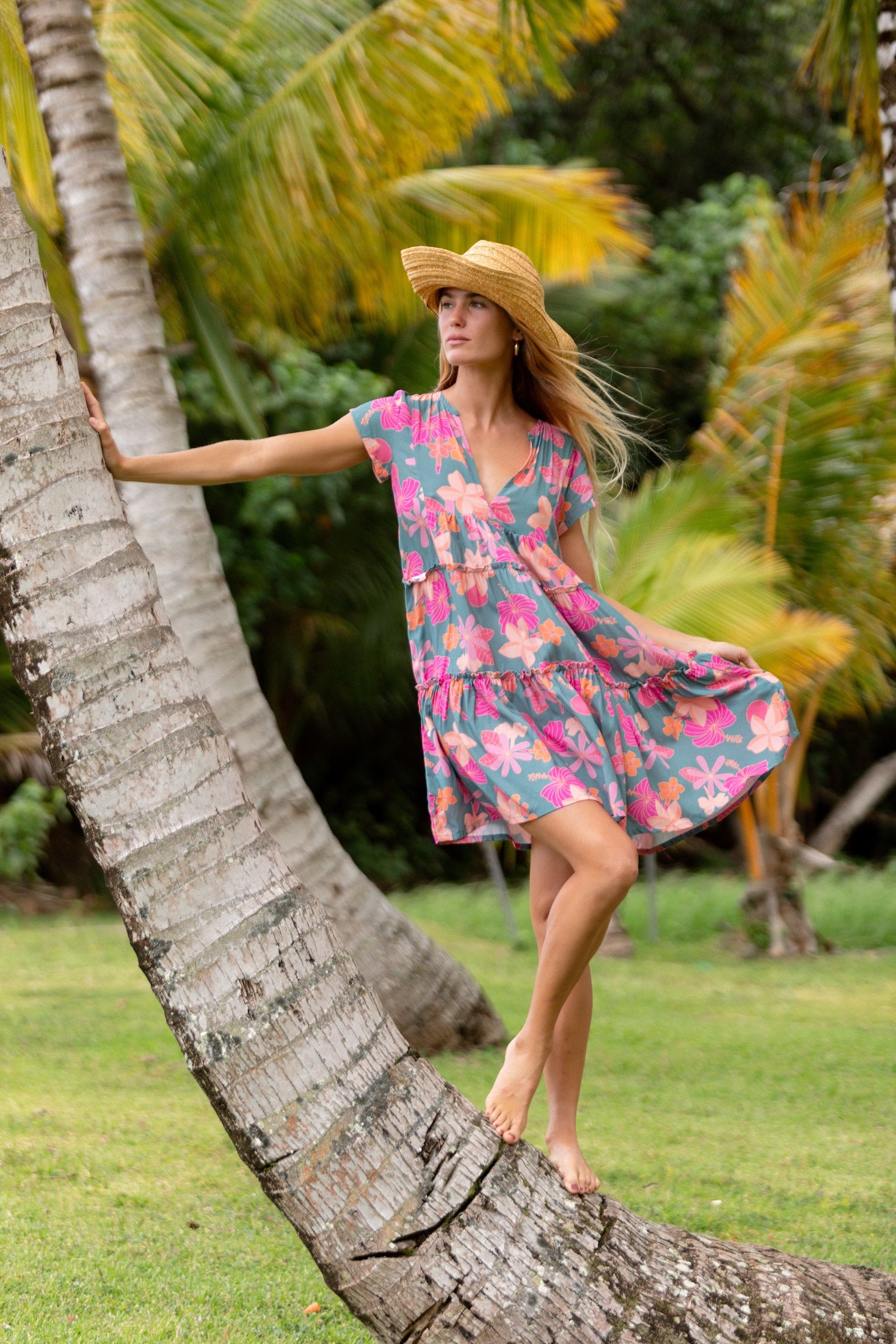 woman with brown hair wearing a teal v neck flowy dress with orange and pink floral print
