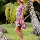 woman with brown hair wearing a teal v neck flowy dress with orange and pink floral print