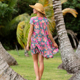 woman with brown hair wearing a teal v neck flowy dress with orange and pink floral print